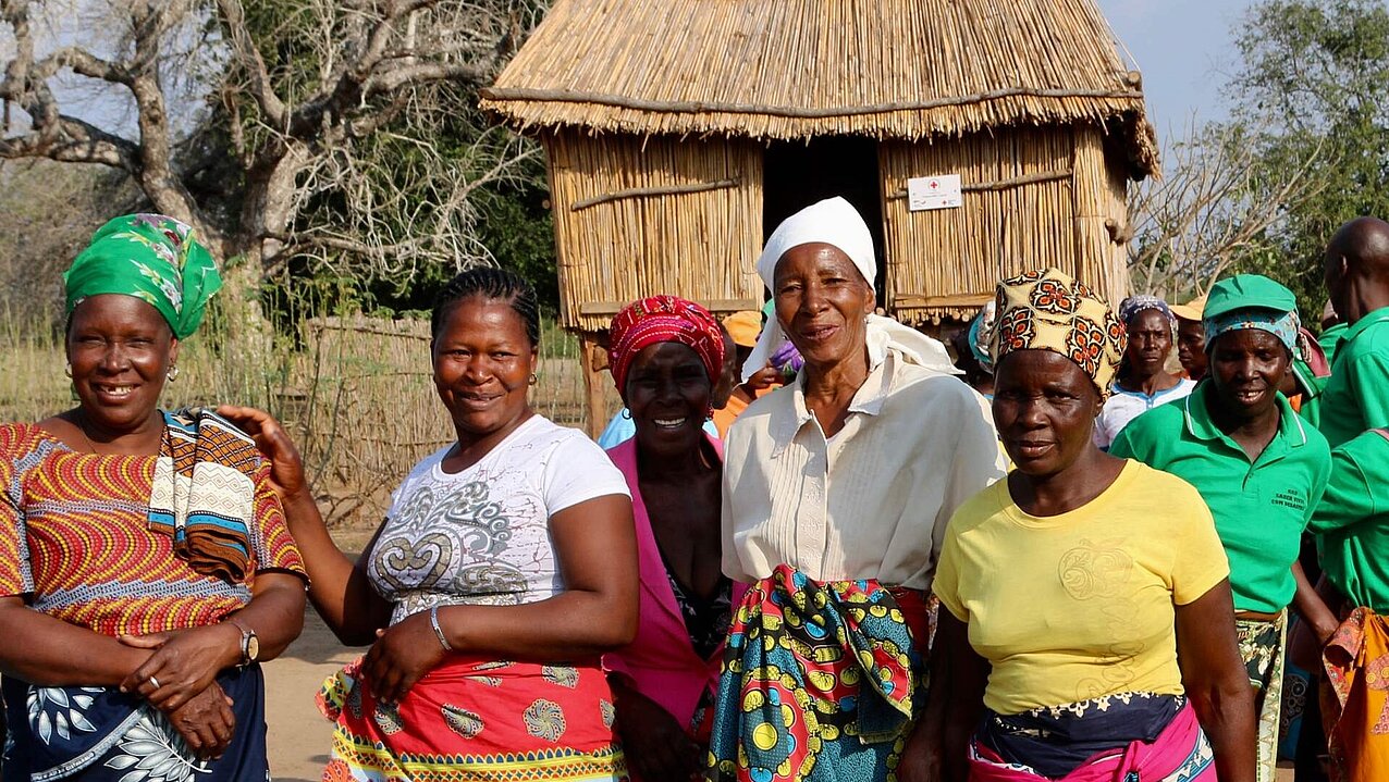 Eine Gruppe Frauen in bunter Kleidung stehen vor einem vom DRK errichteten neuen Kornspeicher.