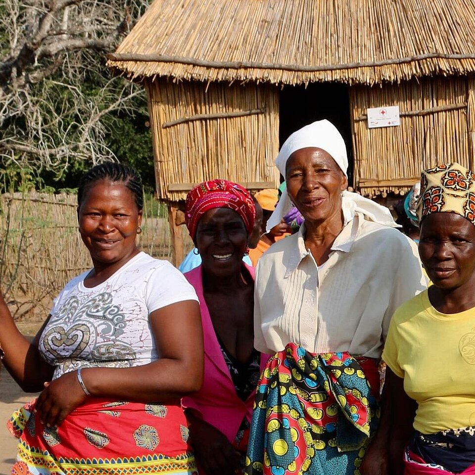 Eine Gruppe Frauen in bunter Kleidung stehen vor einem vom DRK errichteten neuen Kornspeicher.