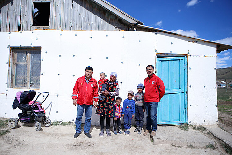 Kirgisische Familie und Rothalbmond-Helfer vor Haus