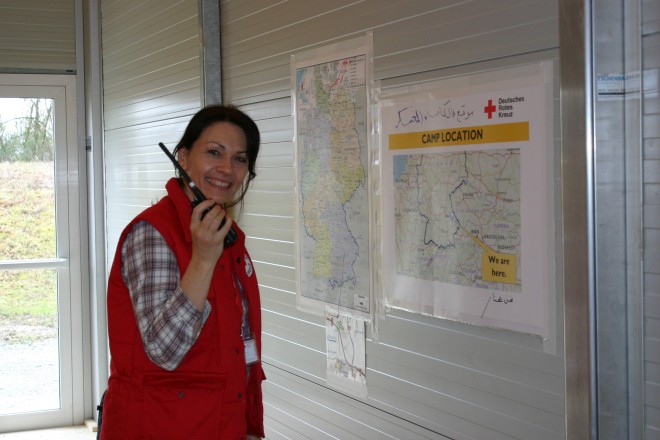 DRK-Mitarbeiterin mit Funkgerät vor Infopostern
