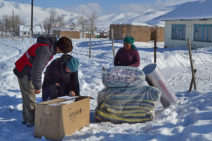 Drei Menschen mit Matratzen und Kiste im Schnee